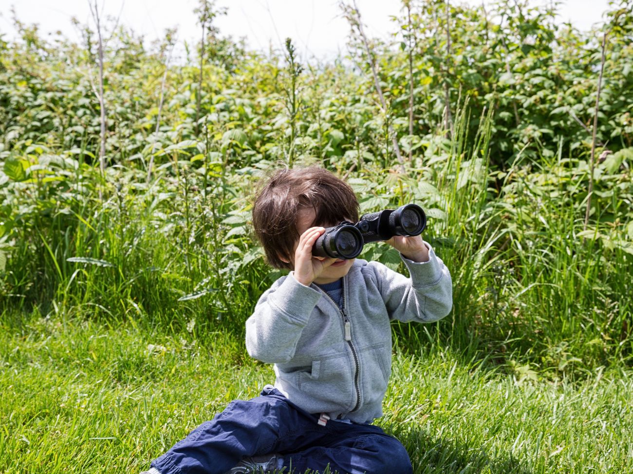 A child bird watching with binoculars